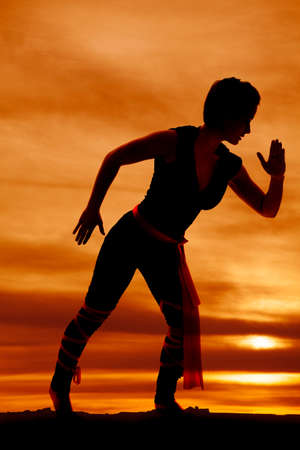 A silhouette of a woman ninja ready to fight.の写真素材