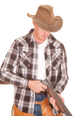 A cowboy looking down at his rifle checking for bullets.の写真素材