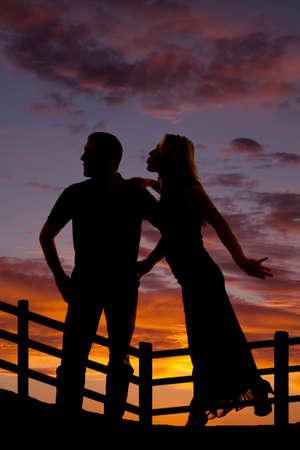a silhouette of a woman trying to lean over and give her cowboy a kiss.の写真素材