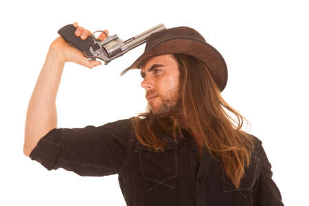 A cowboy holding on to a pistol looking away with a serious expression on his face.の写真素材
