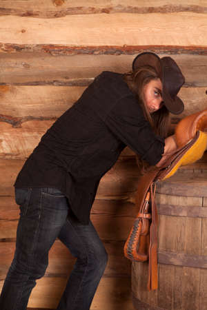 a cowboy holding on to his hat while leaning back on his saddle.の写真素材