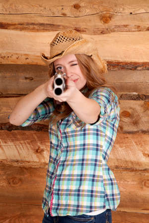 a cowgirl with a shotgun aiming it at the camera.の写真素材