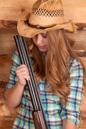 a cowgirl holding on to a shotgun lookign down.の写真素材