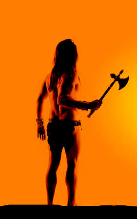 a silhouette of a man holding on to his hatchet.の写真素材