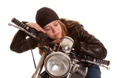 a woman in leather laying on her motorcycle asleep.の写真素材