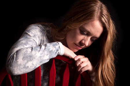 a woman sitting in her chair with her American flag shirt on looking downの写真素材