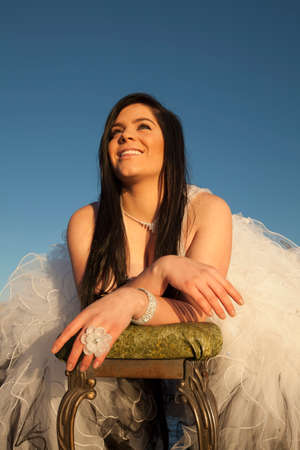 a woman in her formal dress laying on a bench on the ice with a smile on her face.の写真素材