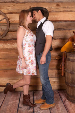 A cowboy is about to kiss his cowgirl in front of a wooden wall.の写真素材
