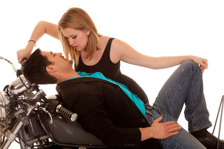 A man laying on his motorbike with his woman leaning over himの写真素材