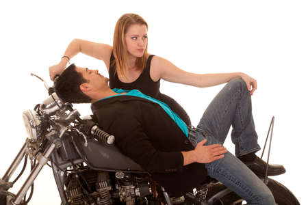 A man laying on his motorbike with his woman leaning over him and looking away.の写真素材