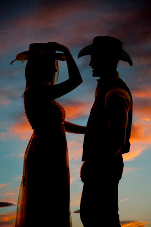A silhouette of a woman in her cowgirl hat looking at her cowboy.の写真素材