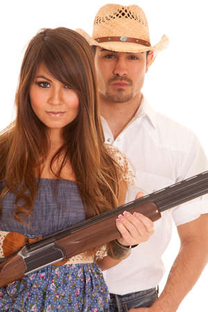 A cowboy standing behind his woman and she is holding the weapon.の写真素材