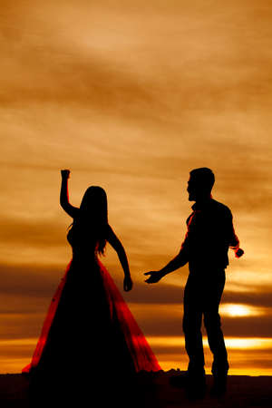 a silhouette of a woman dancing with her man close by.の写真素材