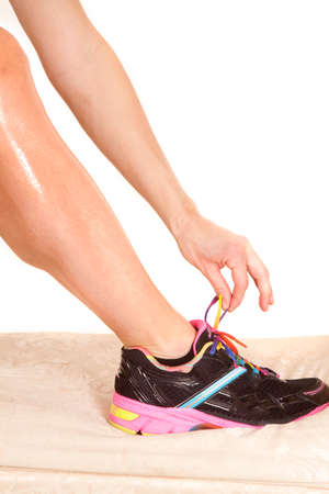A woman with her hand to tie her shoe.の写真素材