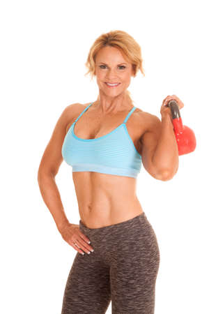 A woman in a blue sports bra holding a kettle bell.の写真素材