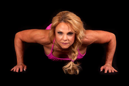 A woman doing a pushup with a serious expression.の写真素材