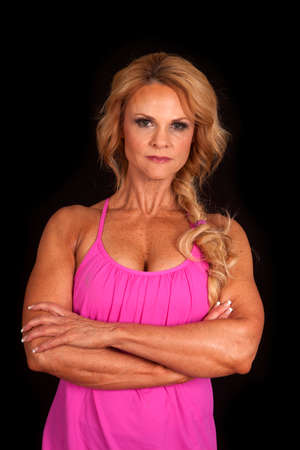 An older woman in a pink sports top with her arms folded.の写真素材