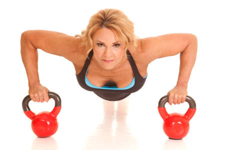 A mature woman doing pushups on kettle bells.の写真素材