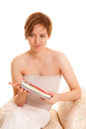 A woman in her fancy dress with a funny expression on her face holding on to a bookの写真素材