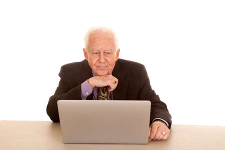An old man sitting at a computer wearing a suit and tie.