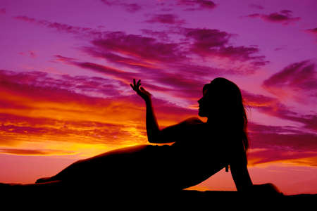 A woman in a swimsuit laying on her side in the sunset.の写真素材