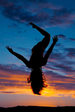 A silhouette of a woman in the sunset free falling.