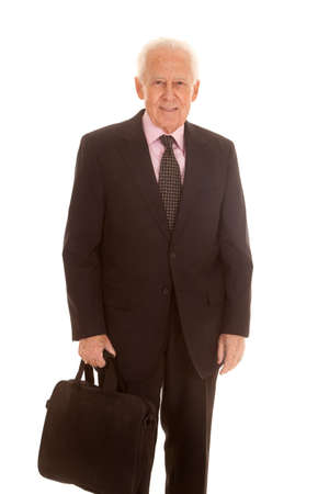An elderly business man standing holding a bag.の写真素材