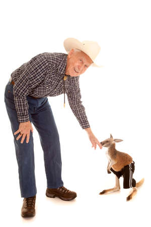 An old cowboy reaching down to a baby kangaroo.の写真素材