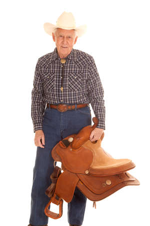 An elderly man standing holding a saddle in his hand.の写真素材