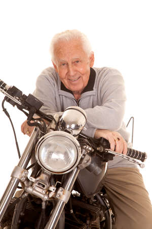 An elderly man sitting on a motorcycle smiling.の写真素材