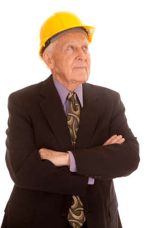 An elderly man in a suitcoat and a yellow hard hat with his arms folded.の写真素材