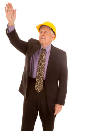 An elderly man in a suit and a hard hat with his hand up.の写真素材