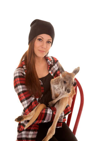 a woman in her beanie sitting on a chair holding on to her baby kangaroo.の写真素材