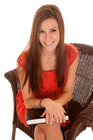 a woman with a smile sitting in her chair with her book.の写真素材