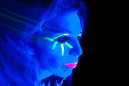 A woman is lit up with a black light looking to the side.の写真素材