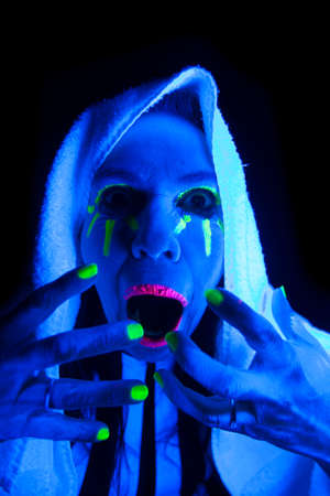 A woman is screaming in the black light with her mouth open.の写真素材