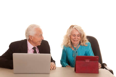 An elderly couple working on a computer and tablet with a smile.の写真素材