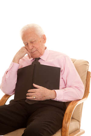 An elderly man falling asleep with a book on his chest.の写真素材