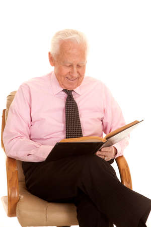 an elderly man with a smile on his face studying a book.の写真素材