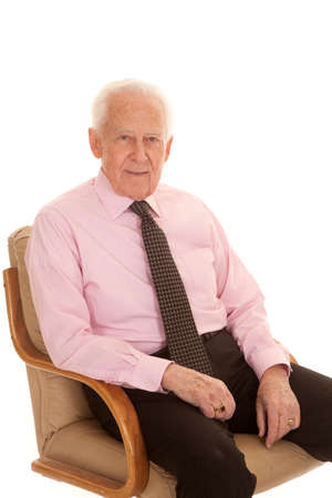 an older man sitting in his chair with a small smile on his lips.の写真素材