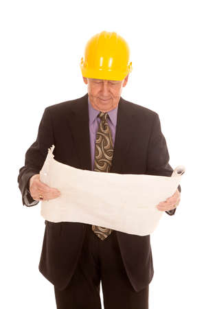 an elderly man wearing his hardhat and looking down at his plans.の写真素材