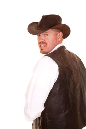 a cowboy in his vest and hat looking over his shoulder with a mad expression on his face.の写真素材