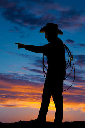 A silhouette of a older cowboy holding on to his rope.の写真素材