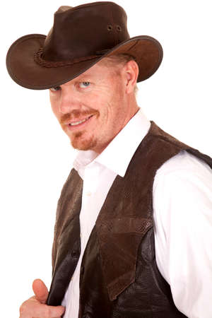 A cowboy in a hat and a vest and white shirt with a smirk on his face.の写真素材