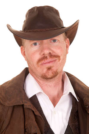 A cowboy in a hat and a vest and white shirt with a smirk on his face.の写真素材