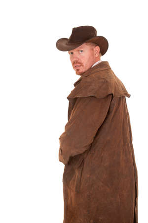 A cowboy in a leather coat looking back with a scared look on his face.の写真素材