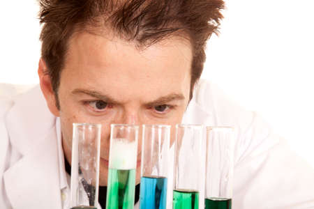 A man is looking at test tubes with blue and green chemicals in them.の写真素材