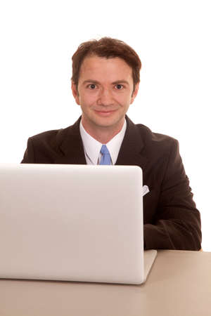 A man in a suit is sitting at a computer with a smile.の写真素材