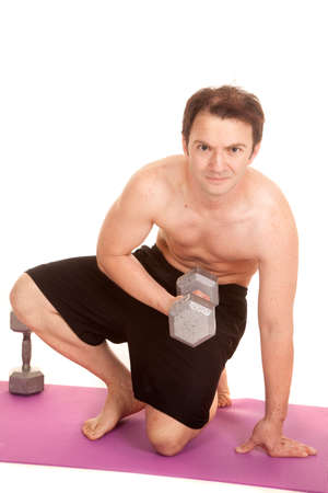 A man in shorts holding a weight kneeling doing a curl.の写真素材