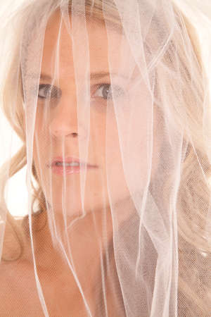 A bride with a veil over her face up close looking.の写真素材